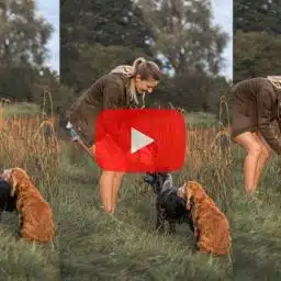 Video thumbnail: a woman with two dogs in a grassy field, bending to pet them; a red play button overlays the center.